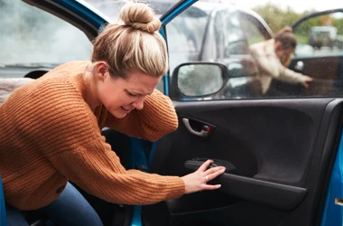 Chiropractic Phoenix AZ Auto Injury BOX A young woman holding her neck in pain and climbing out of her car after an auto accident