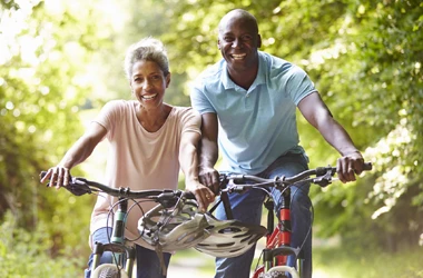 Chiropractic Phoenix AZ Wellness BOX A smiling couple biking through a wooded area on a sunny day