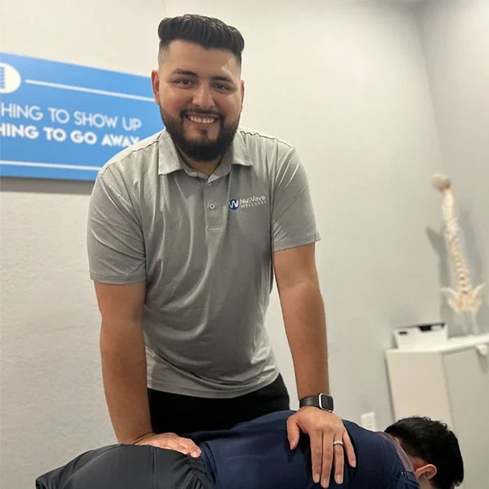 Chiropractor Phoenix AZ Juan Alvarez HP About Dr. NuWave Wellness posing for a photo after an adjustment on a patient's back